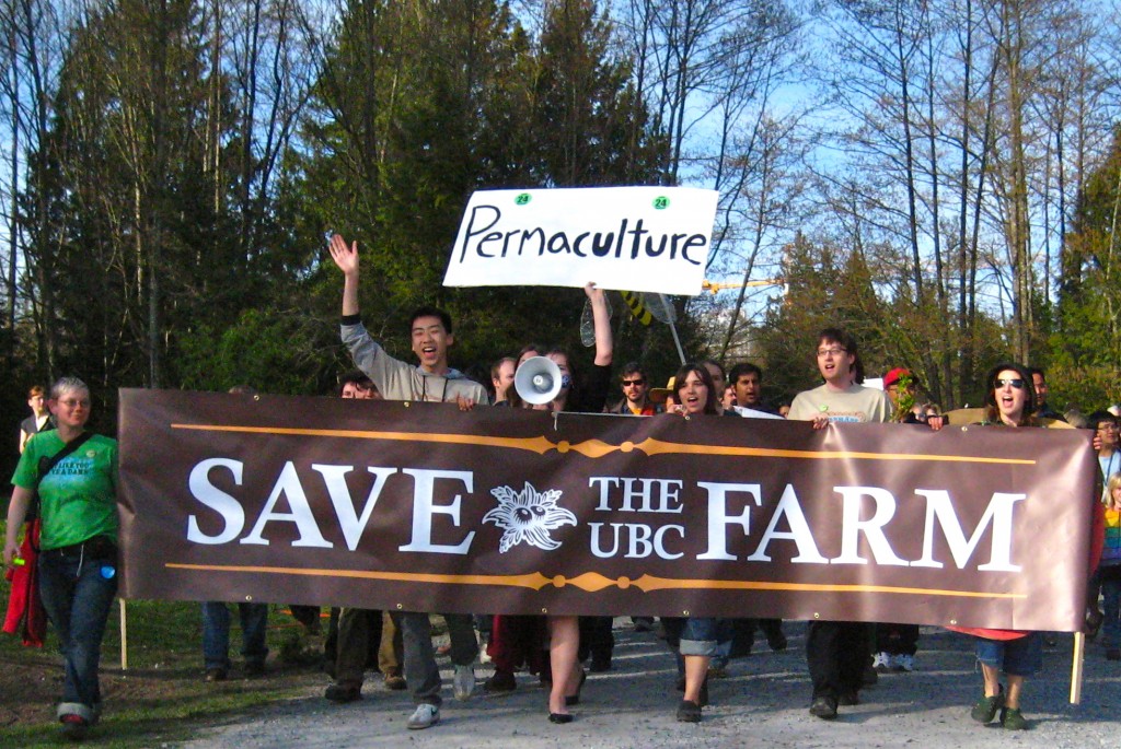 A group of people celebrating and holding a Save the UBC Farm banner.